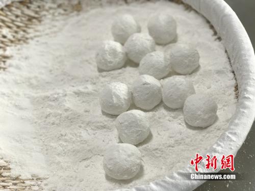 "制作元宵時，首先要將餡料做好，沾上水，再投進(jìn)盛滿糯米粉的笸籮內(nèi)搖。<a