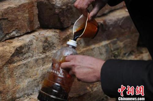 一名村民將不明液體灌入透明飲料瓶內(nèi)?！　∶厦?攝