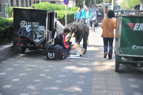 圖為快遞小哥在路邊配送快遞。呂春榮 攝