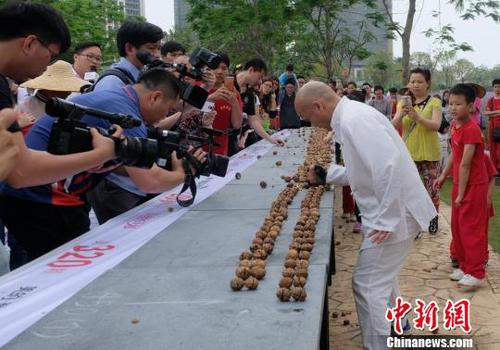 黎偉軍手劈核桃現(xiàn)場(chǎng)吸引不少人圍觀?！〕叹皞?攝