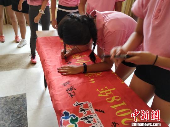 營員朱子慧正在夏令營營旗上一筆一劃地簽名，因為比較少寫漢字，她的字跡稍顯幼稚?！×謺缘?攝