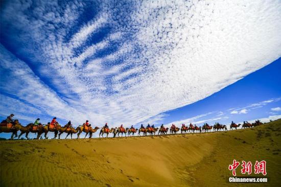 資料圖：甘肅敦煌鳴沙山月牙泉景區(qū)藍(lán)天、白云、黃沙相映成趣，每天吸引數(shù)萬中外游客觀光游覽。 王斌銀 攝