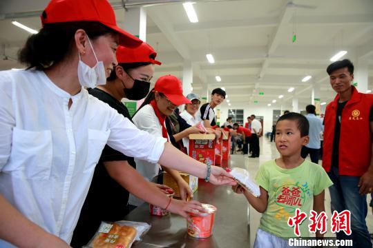8月24日，志愿者在濰坊壽光市營(yíng)里鎮(zhèn)第二初級(jí)中學(xué)安置點(diǎn)為災(zāi)民發(fā)放救援物資?！×籂?攝