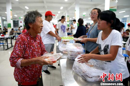 8月24日，志愿者在濰坊壽光市營(yíng)里鎮(zhèn)第二初級(jí)中學(xué)安置點(diǎn)為災(zāi)民發(fā)放救援物資?！×籂?攝
