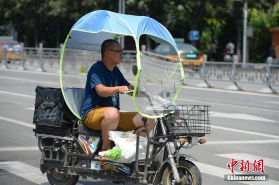資料圖：男子在電動(dòng)車上撐起遮陽棚。<a target='_blank' href='http://www.chinanews.com/'>中新社</a>記者 劉文華 攝