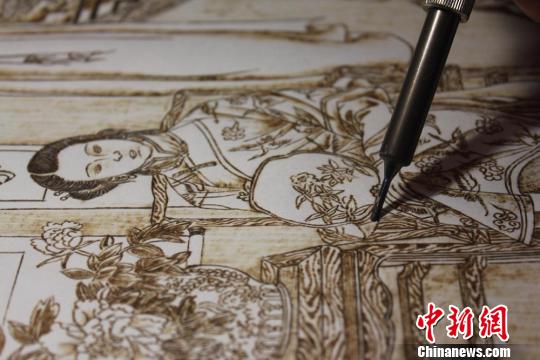 圖為正在創(chuàng)作中的烙畫作品?！⌒煅?攝