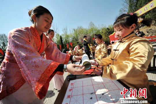 圖為曲阜舉行學(xué)童啟蒙開筆禮儀式?！∏肥形麄鞑抗﹫D 攝