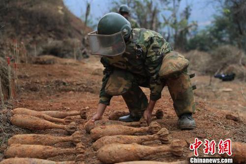 中國(guó)人民解放軍南部戰(zhàn)區(qū)陸軍云南掃雷大隊(duì)在雷場(chǎng)掃雷期間，一名戰(zhàn)士將一枚搜排出來的炮彈放至臨時(shí)存放點(diǎn)?！蠲?攝