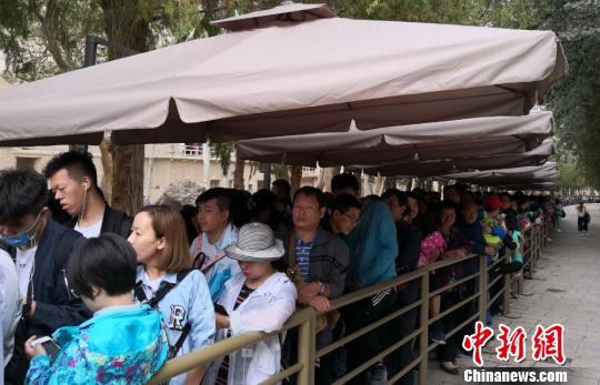 圖為2018年8月中旬，莫高窟前等候參觀的應急游客排成近1公里長隊。(資料圖) 馮志軍 攝