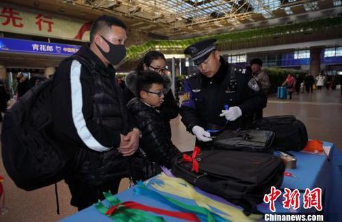 12月28日，北京西站派出所民警為背黑色雙肩包的旅客系上個(gè)性小標(biāo)識(shí)，以防在通過安檢或乘車過程中出現(xiàn)錯(cuò)拿情況。(完) 龐賀雷 攝