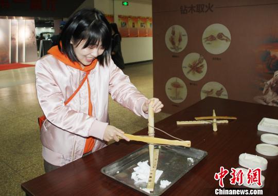 參觀者現(xiàn)場體驗“鉆木取火”。　徐巧明 攝