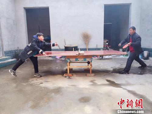 圖為劉奉智父親用自制的乒乓球臺(tái)陪劉奉智打乒乓球。　郝學(xué)娟 攝