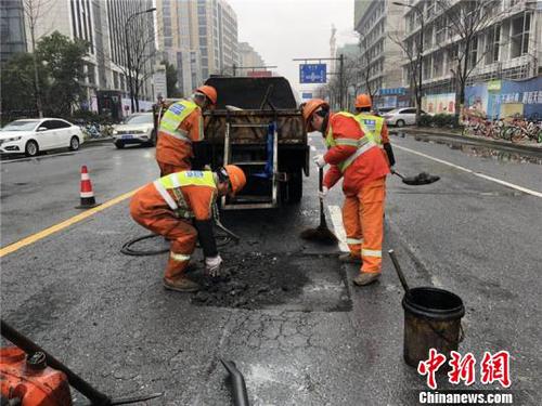 環(huán)衛(wèi)工人修補雨天侵蝕的瀝青路面?！∥骱^(qū)城管局提供 攝