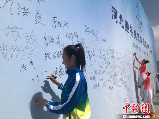 圖為河北迎冬奧青年志愿者、張家口機械工業(yè)學校教師游洋在啟動儀式現(xiàn)場主題背景墻上簽名。　宋敏濤 攝