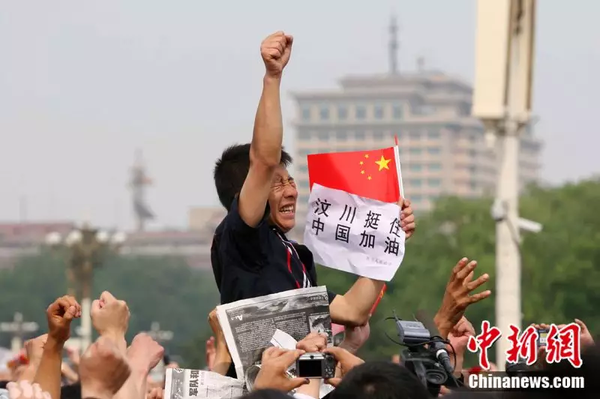 2008年5月19日，北京天安門廣場上的民眾為地震遇難者默哀，一位來自四川的男子高舉右手為家鄉(xiāng)加油。中新社記者 富田 攝