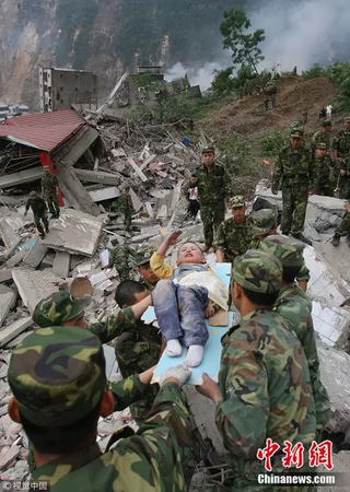 2008年5月13日，3歲的郎錚因為躺在擔(dān)架上向解放軍戰(zhàn)士敬禮。 楊衛(wèi)華 攝 圖片來源：視覺中國