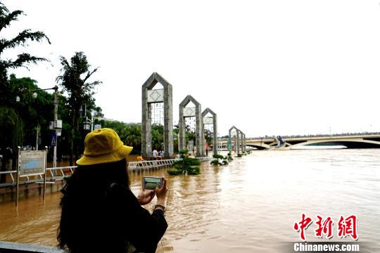 圖為一民眾在桂林解放橋?yàn)I江路拍攝洪水?！√茐魬?攝