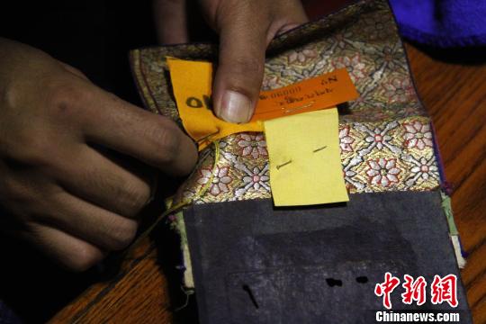 圖為羅布林卡管理處工作人員將編號(hào)縫在古籍外側(cè)?！≮w朗 攝