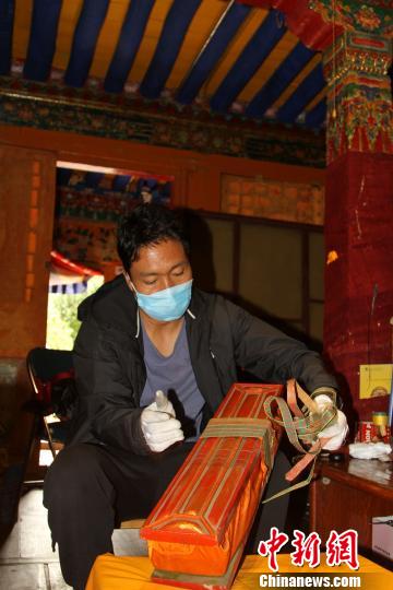 圖為西藏自治區(qū)古籍保護(hù)中心古籍保護(hù)部副主任才洛打開(kāi)古籍進(jìn)行登記?！≮w朗 攝