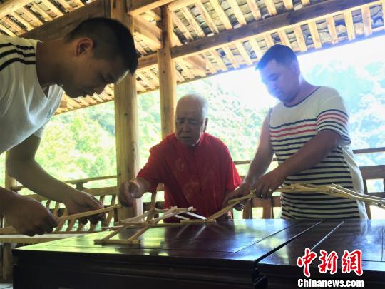 圖為黃春財(cái)與兒子、孫子共同演示木拱廊橋搭建。　葉茂 攝