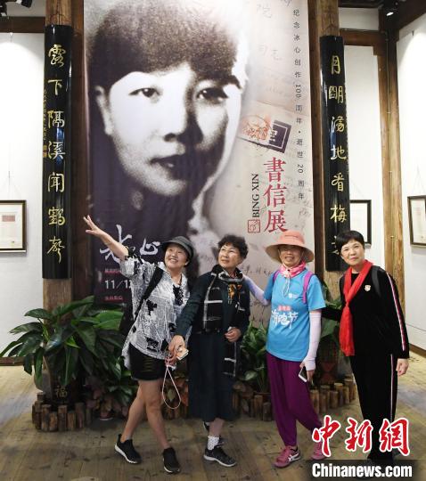 觀眾在展出的冰心青年時期黑白老照片前合影?！∮浾邉⒖筛?攝