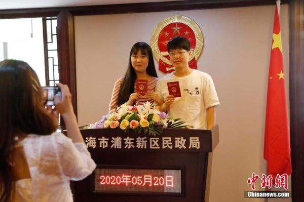 資料圖：兩位市民手持結(jié)婚證合影留念。 殷立勤 攝
