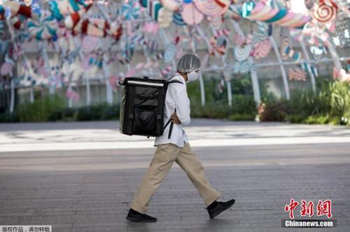 資料圖：當(dāng)?shù)貢r(shí)間2021年1月4日，泰國曼谷，一名快遞員“全副武裝”走在街頭。