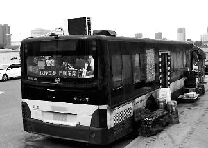 路邊停放的公交車頂上的空調十分顯眼，旁邊碼放著座椅、遮陽棚、啤酒等物?？导?攝